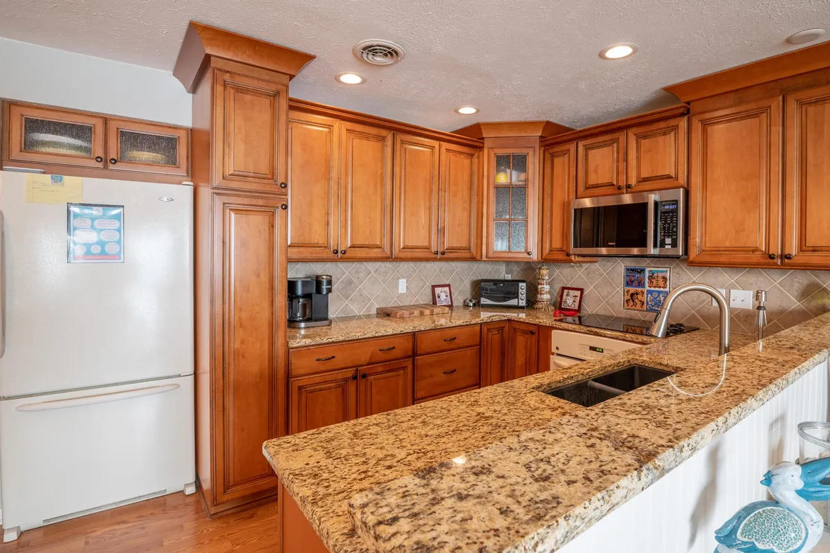 A modern, well-equipped kitchen with granite countertops, wood cabinetry, and stainless steel appliances. The kitchen island invites guests to gather for meal prep or casual conversations, reflecting the section's emphasis on gourmet cooking and entertaining.