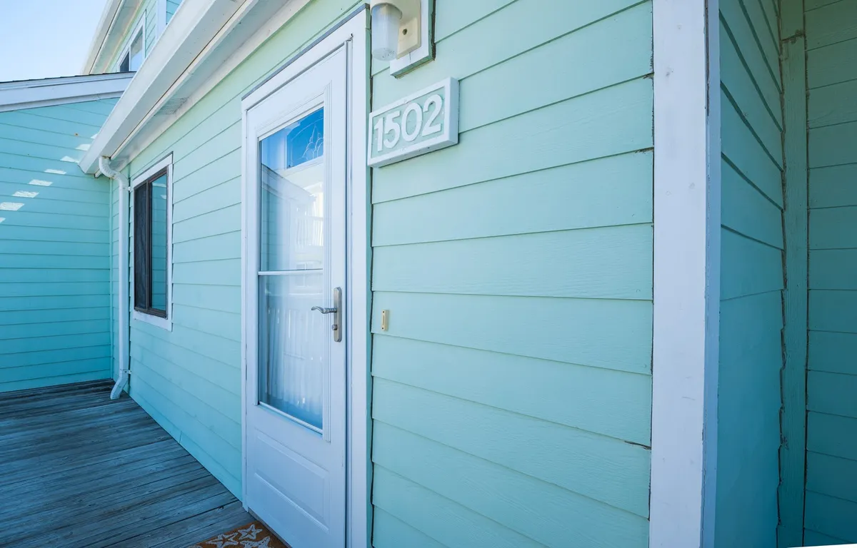 A welcoming exterior shot of the front door with the house number clearly visible, set against a fresh exterior color palette. The entryway is inviting, offering the first impression of a secure and private space.
