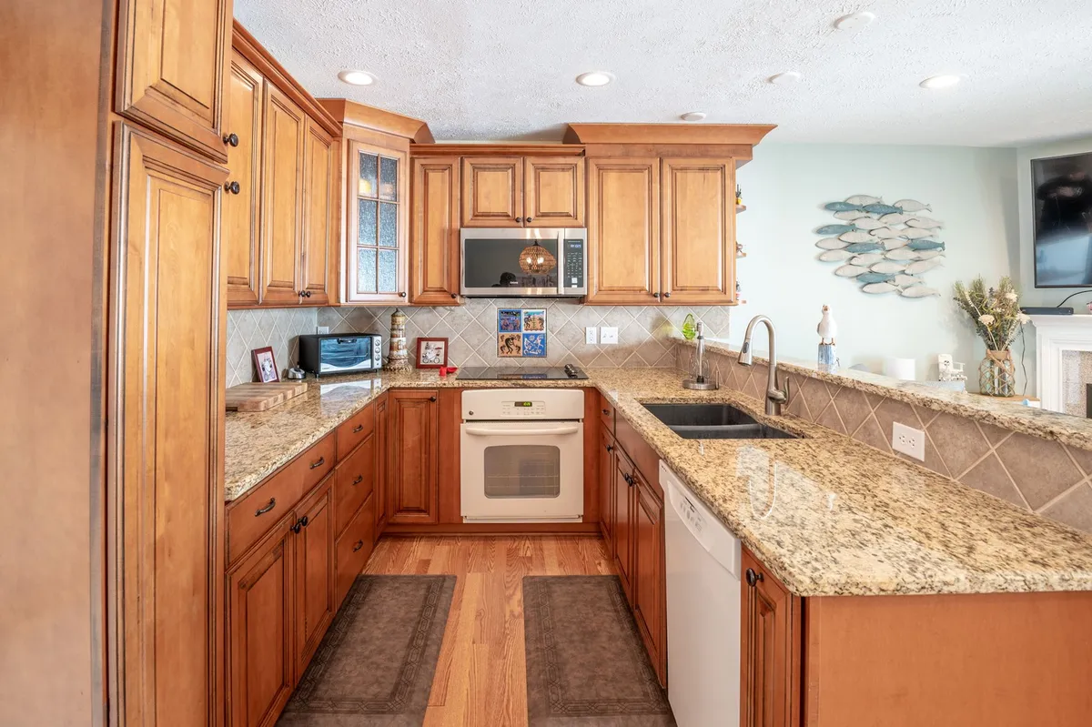 A modern kitchen space with granite countertops, wooden cabinetry, and stainless steel appliances, including a stove and sink area. The layout is open and inviting, ideal for self-catering and meal preparation.