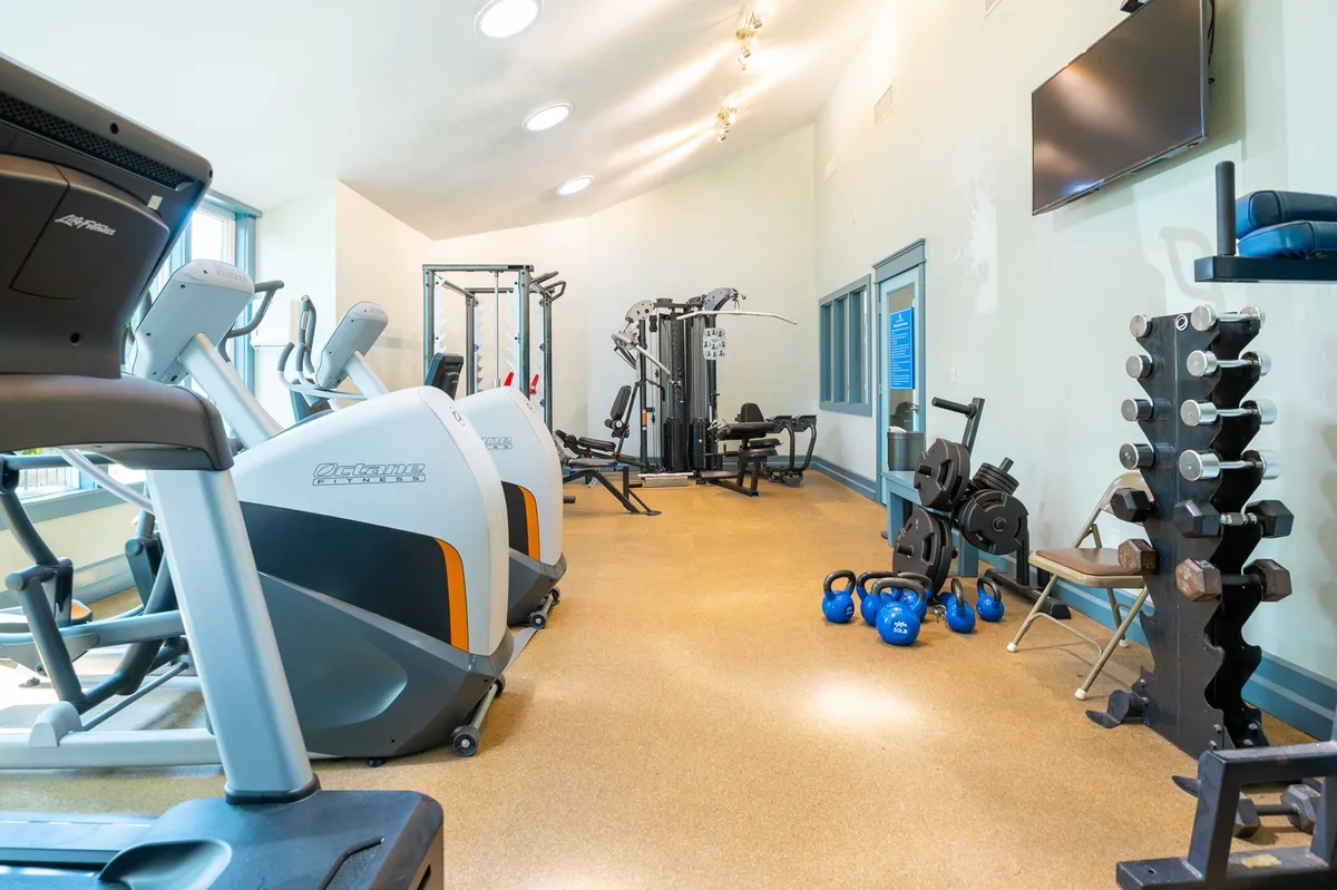 A well-equipped fitness center is presented, filled with cardio machines, weightlifting equipment, and free weights. The atmosphere is vibrant and energetic, encouraging guests to work out or join group classes as part of their wellness routine.