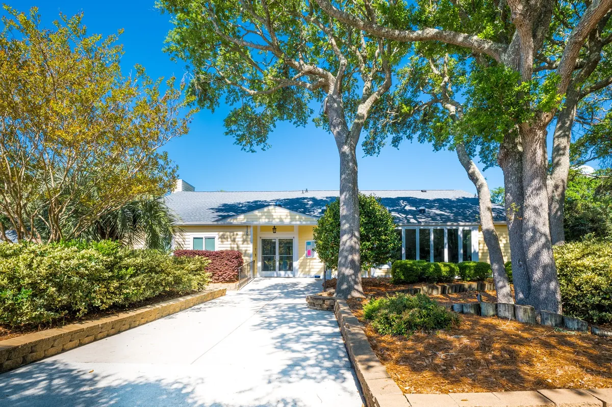 A beautifully landscaped entrance framed by large trees and lush gardens, setting a welcoming tone. The main entryway invites guests to step into an oasis of comfort and tranquility.
